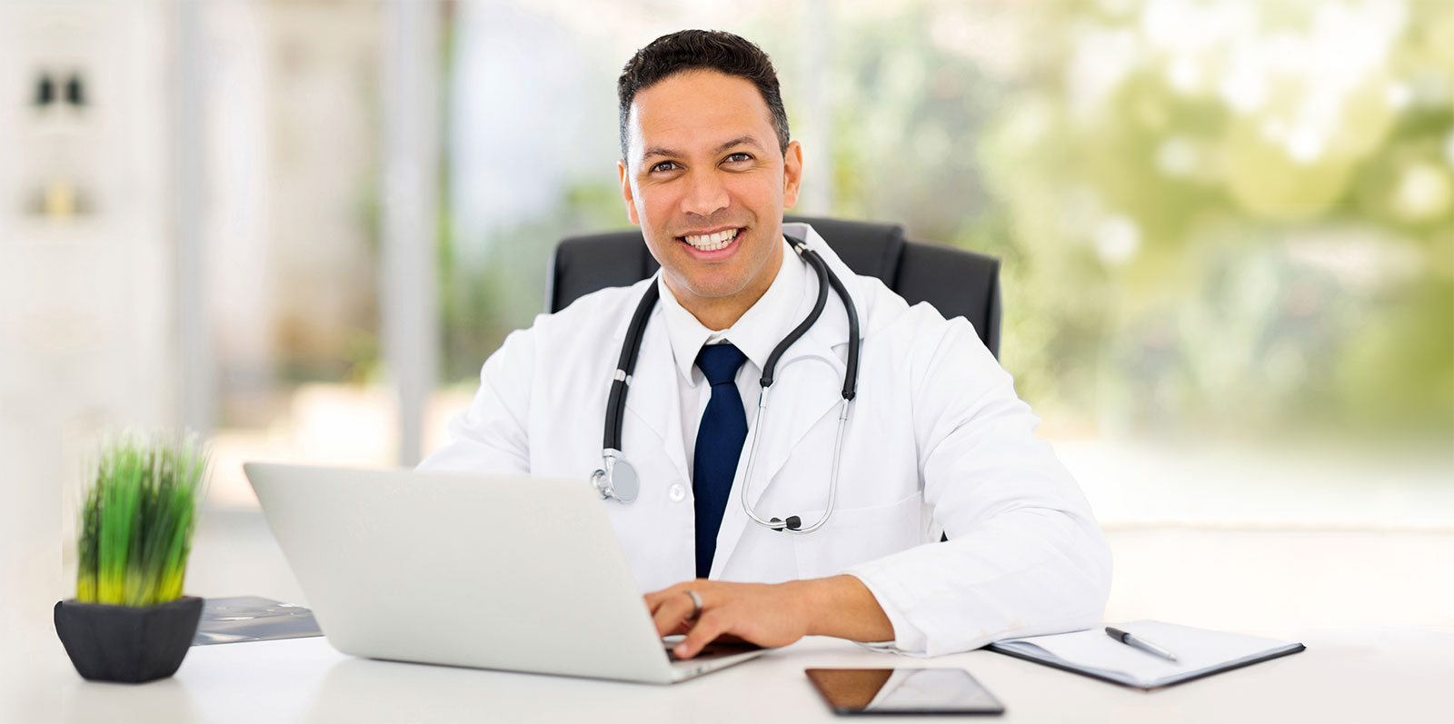Physician at a desk using a laptop to manage diagnostic care